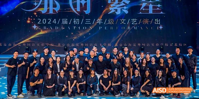 A large group of students and teachers from Beijing Haidian Foreign Language Academy in black uniforms posing for a group photo under a banner for the "2024 Kangjiaying Performance."