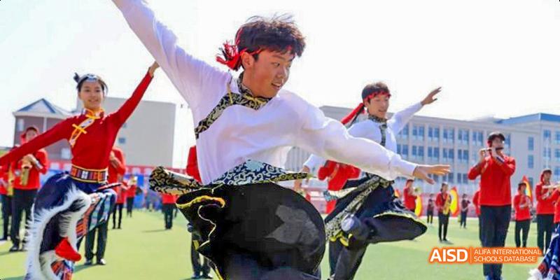 A student from Beijing Haidian Foreign Language Academy performing a traditional dance outdoors in a white shirt and black skirt.