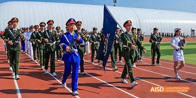 A student marching band or group from Beijing Haidian Foreign Language Academy in uniform, marching on a track.