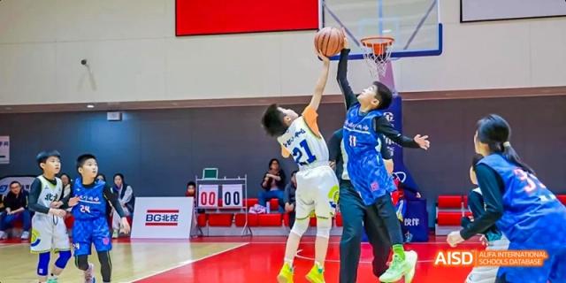 Two male students from Beijing Haidian Foreign Language Academy playing basketball during a game.