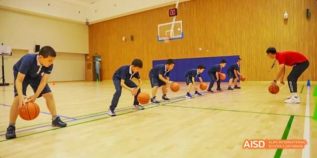 Students from Beijing Haidian Foreign Language Academy practicing basketball drills, bouncing balls on the court.