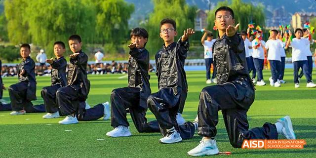 Students from Beijing Haidian Foreign Language Academy in camouflage uniforms practicing military-style formation on a field.