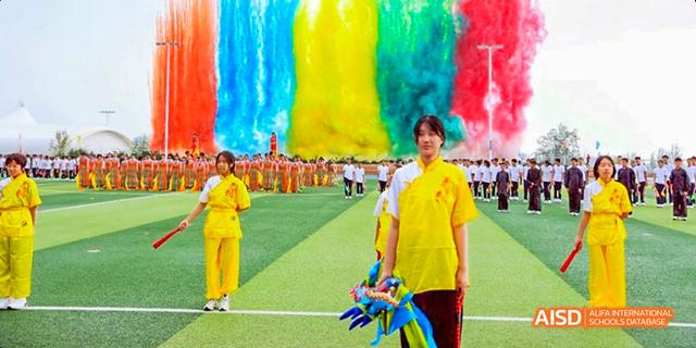 A student from Beijing Haidian Foreign Language Academy in a yellow uniform holding colorful ribbons during a performance.