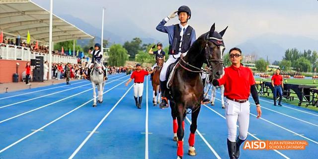 A student from Beijing Haidian Foreign Language Academy riding a horse on a track during a sports event.