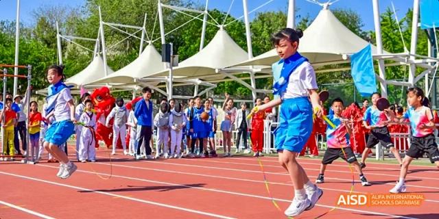 Students from Beijing Haidian Foreign Language Academy celebrating with flags during a large outdoor event.