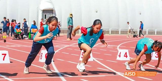 Female students from Beijing Haidian Foreign Language Academy at the starting line of a race on a running track.