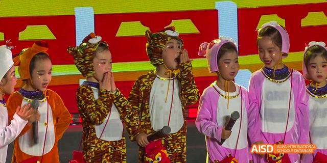 Two young students from Beijing Haidian Foreign Language Academy singing in colorful costumes on a stage.