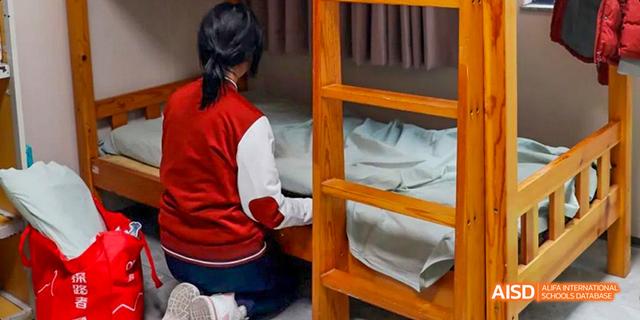 A female student from Beijing Haidian Foreign Language Academy organizing a bunk bed in a dormitory.