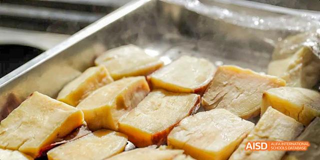 A close-up of a tray of sliced food, possibly potatoes, in the cafeteria of Beijing Haidian Foreign Language Academy.