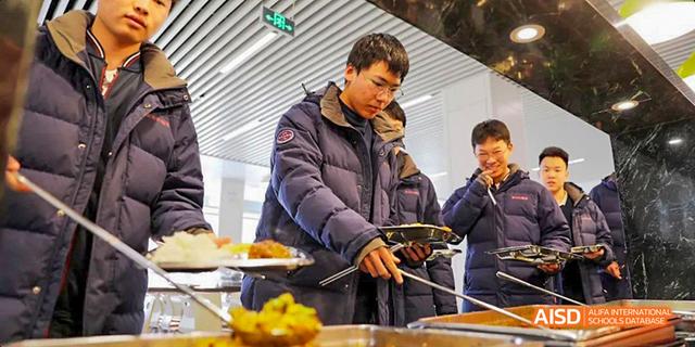 A male student from Beijing Haidian Foreign Language Academy serving himself food in the school cafeteria.