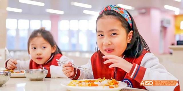 A young girl from Beijing Haidian Foreign Language Academy eating her meal with a spoon.