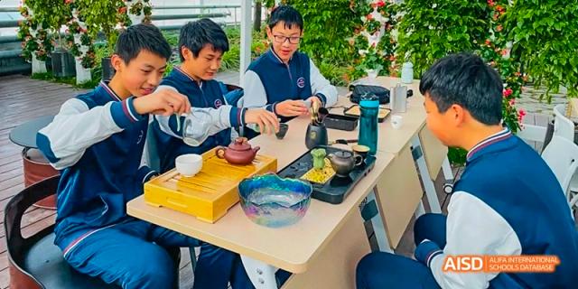 Students from Beijing Haidian Foreign Language Academy gathered around a table for a hot pot or cooking activity.