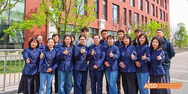 A group of students and teachers standing together for a photo outside a building at Beijing Hui Xian School.