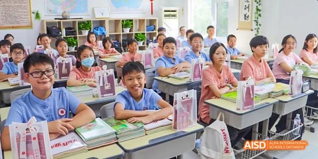 Students in a classroom, with one student smiling at the camera at Beijing Hui Xian School.
