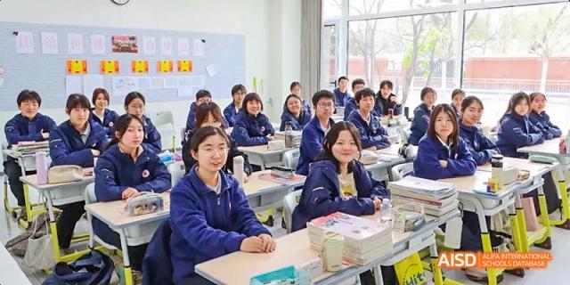 A classroom of students seated at their desks, listening to a lesson at Beijing Hui Xian School.