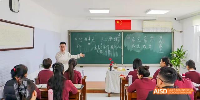 A teacher standing in front of a chalkboard, giving a lesson to a class at Beijing Hui Xian School.