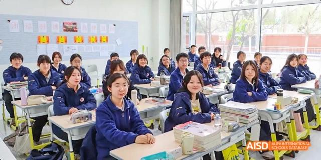 A classroom full of students sitting at their desks, listening attentively at Beijing Hui Xian School.