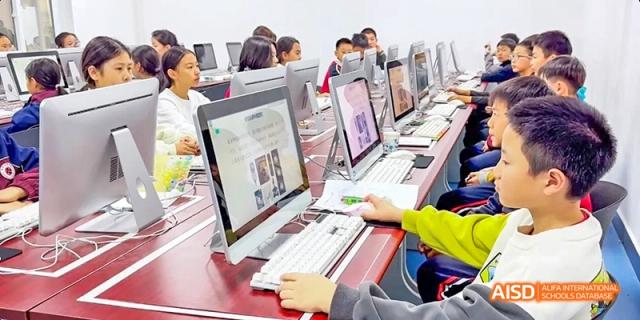 Students sitting at computers in a lab, focused on their screens at Beijing Hui Xian School.