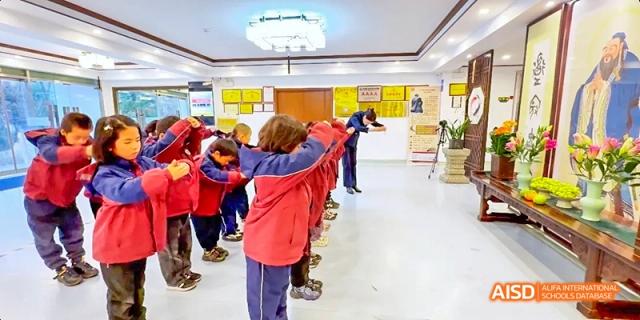 Young students standing in a line in a hallway at Beijing Hui Xian School.
