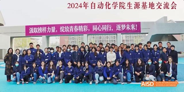 A large group of students in blue tracksuits posing together for a group photo at Beijing Hui Xian School.