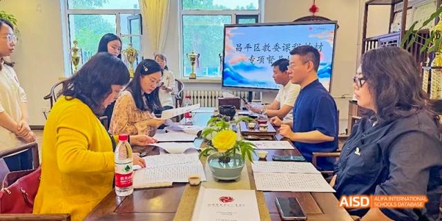 People sitting at a table with laptops, having a meeting or discussion at Beijing Hui Xian School.