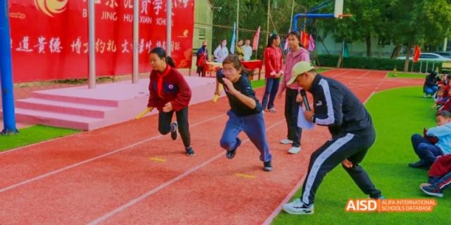 Students running a race on a track, focused on the finish line at Beijing Hui Xian School.
