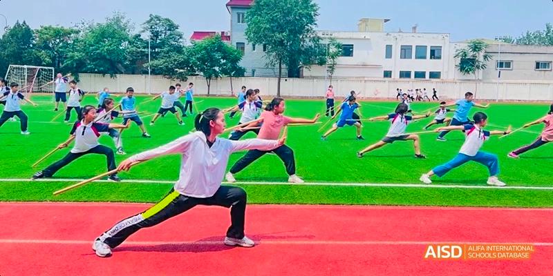 A group of students doing stretching exercises or yoga on a green field at Beijing Hui Xian School.