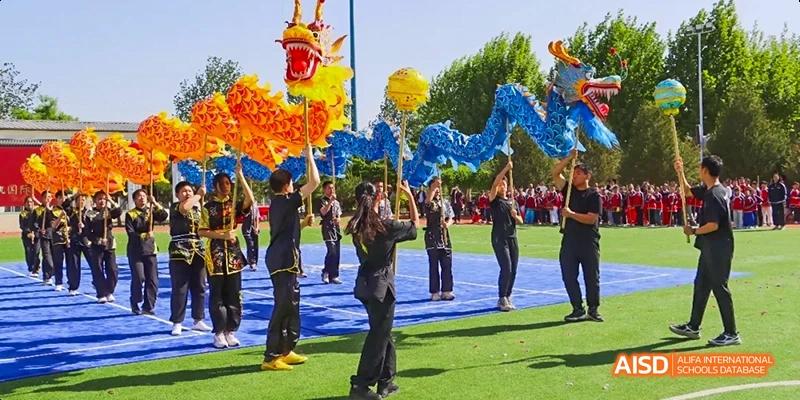 Students in a traditional dragon costume performing outdoors at Beijing Hui Xian School.