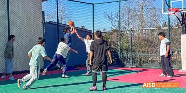 Students playing a game of basketball on an outdoor court at Beijing Hui Xian School.