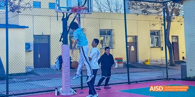 Students shooting hoops on an outdoor basketball court at Beijing Hui Xian School.
