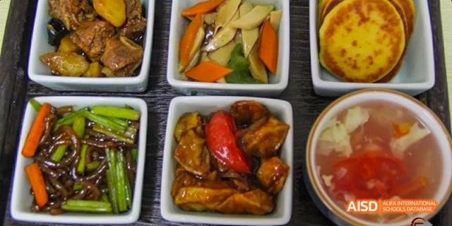 A variety of cooked dishes displayed side-by-side, including meat and vegetables, at Beijing Hui Xian School.