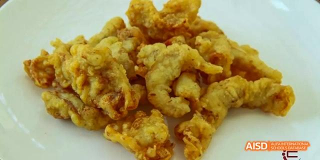 A close-up shot of a plate of fried chicken or a similar meat dish at Beijing Hui Xian School.