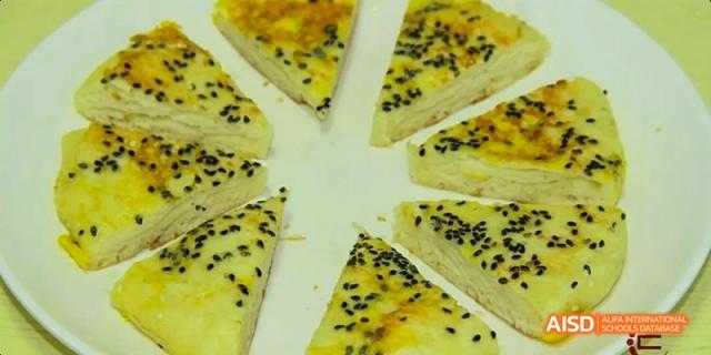 Sliced triangular pieces of food, possibly a savory pastry, sprinkled with black sesame seeds at Beijing Hui Xian School.