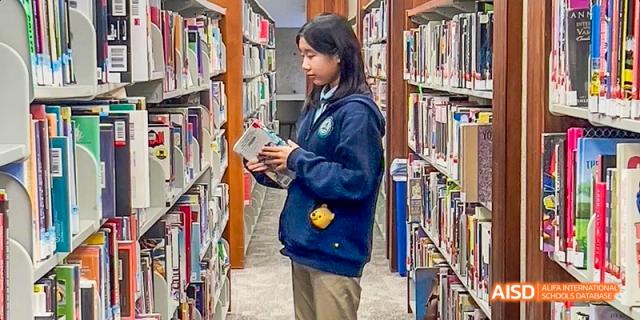 A female student from Beijing Huijia Private School reads a book in the library.