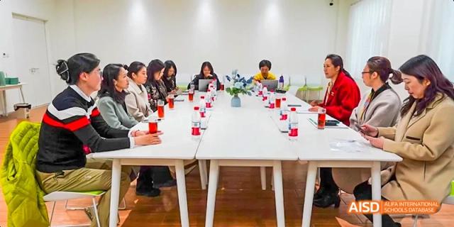 A group of students from Beijing Huijia Private School are seated around a table in a conference room.