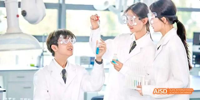 Two students from Beijing Huijia Private School in lab coats are in a lab, working on a science experiment.