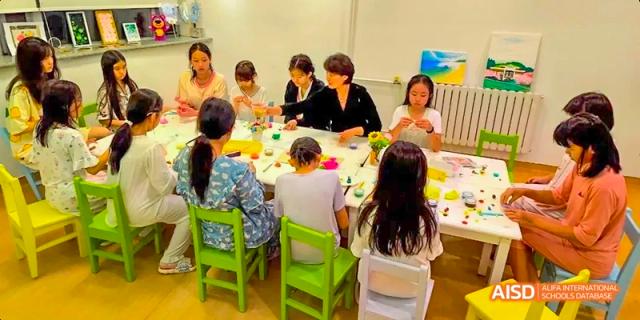A group of students from Beijing Huijia Private School are seated around a table, participating in an activity.
