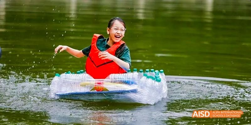 A person at Beijing Huijia Private School rides an inner tube on the water, pulled by a boat.