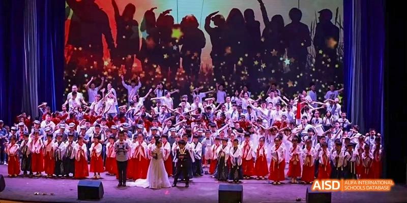 A large group of students from Beijing Huijia Private School performs on a stage.