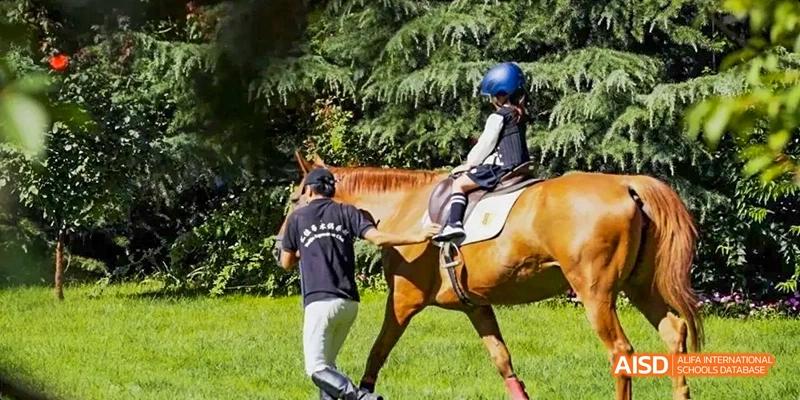 A student at Beijing Huijia Private School rides a horse with a trainer.