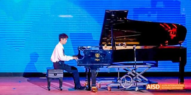 Two students at Beijing Huijia Private School perform a piano duet on a stage.