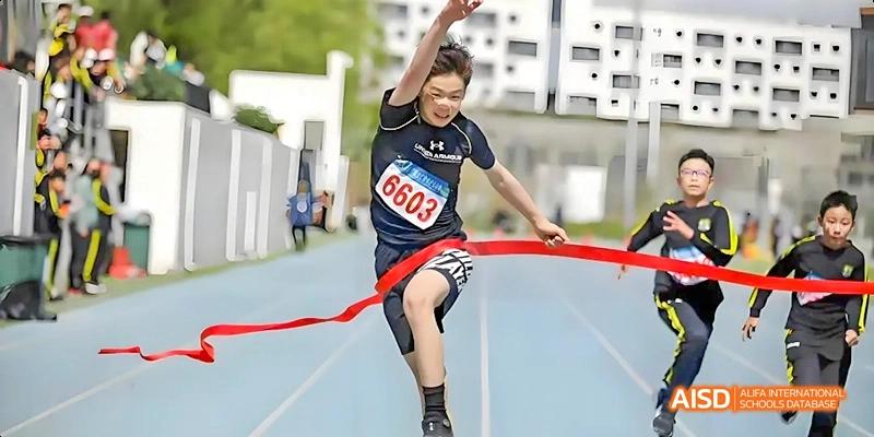 A student from Beijing Huijia Private School crosses the finish line on a running track.