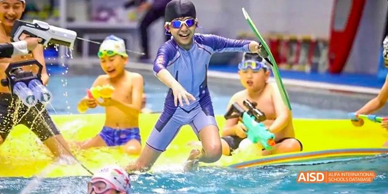 Young students from Beijing Huijia Private School in a swimming pool, participating in a water activity.