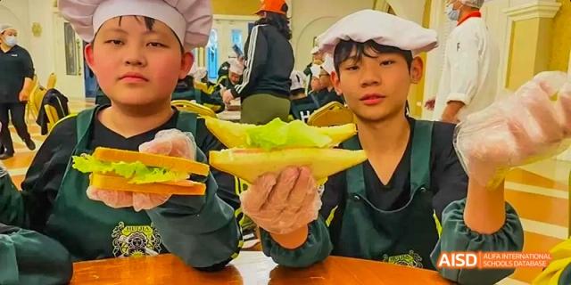 Students at Beijing Huijia Private School proudly hold up a dish they've prepared, showcasing their culinary skills.