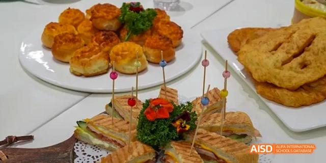 An assortment of small sandwiches, pastries, and other light bites on a platter, served at an event at Beijing Huijia Private School.