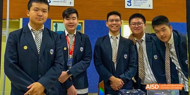 Four male students in school uniforms with ties posing for a group photo at Beijing International Bilingual Academy.