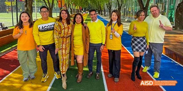 A close-up of a group of people in yellow outfits standing on a running track at Beijing International Bilingual Academy.