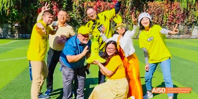 An adult man in a blue shirt dancing with a woman in a yellow dress at an outdoor event at Beijing International Bilingual Academy.