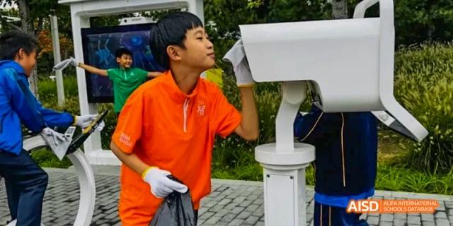 A boy in an orange shirt interacting with an outdoor security camera at Beijing International Bilingual Academy.