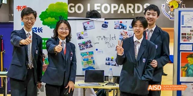 Two students giving a thumbs-up in front of a whiteboard and projector screen at Beijing International Bilingual Academy.